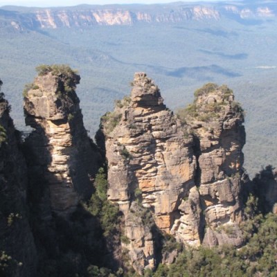 a person standing on a rocky hill with Three Sisters in the background